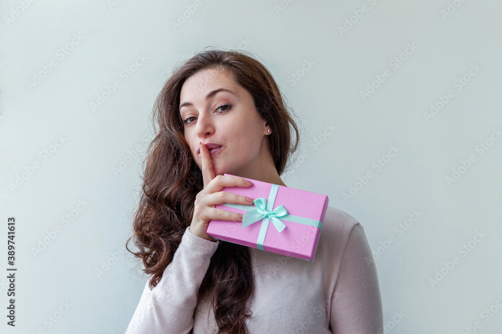 Young positive woman holding small pink gift box isolated on white background. Preparation for holiday. Girl looking happy and excited. Christmas birthday valentine celebration present concept. Young positive woman holding small pink gift box isolated on white background. Preparation for holiday. Girl looking happy and excited. Christmas birthday valentine celebration present concept.