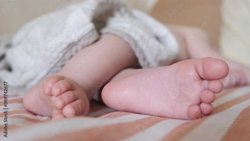 Little feet of a newborn baby. Baby sleeping sweetly in a comfortable bed. Little baby feet skin in close-up. Little feet of a newborn baby. Baby sleeping sweetly in a comfortable bed. Little baby feet skin in close-up.
