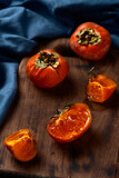 Persimmon on a wooden tray, dark background. View from above. Place for text, autumn fruits, harvest