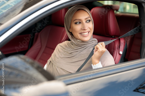 Smiling Muslim Lady In Hijab Putting On Seat Belt