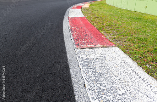 Close up of rough curb at right turn on motor sport track with green field and black asphalt © fabioderby