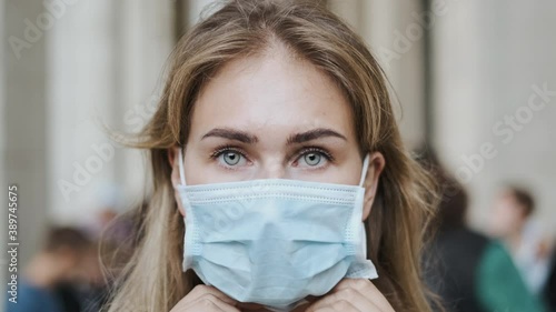 Attractive woman puts mask closeup background Italian columns in crowd people. Looking at camera coronavirus covid 19. Masked face covid-19. Girl putting masks close up in crowded italy corona virus. photo