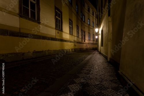  light from street lights and a paved sidewalk made of cobblestones in a street in the old town of prague at night