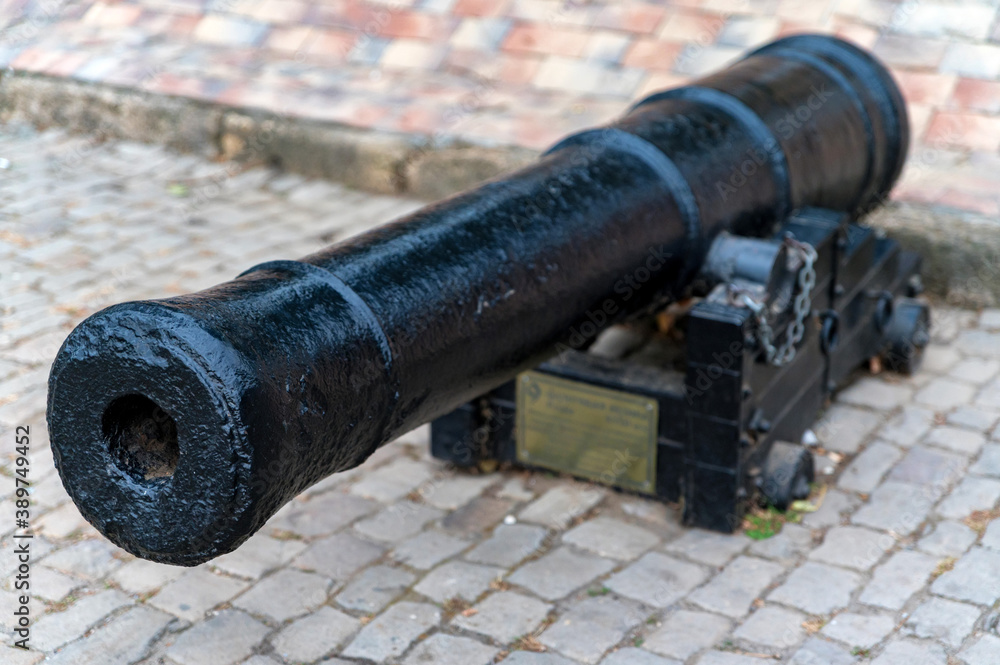 Close up of old antique black canon stands on paving stones