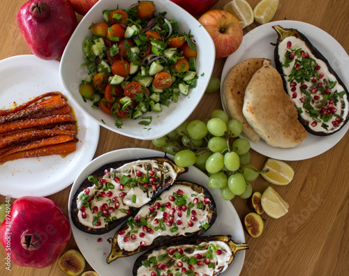 Grilled eggplants, salad, caramelized carrots and fresh fruits on wooden table. Top view photo of different vegetarian meals. 