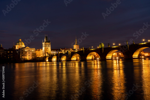
illuminated stone monument of Charles Bridge from the 14th century on the Vltava river and lights from street lighting in the center of Prague