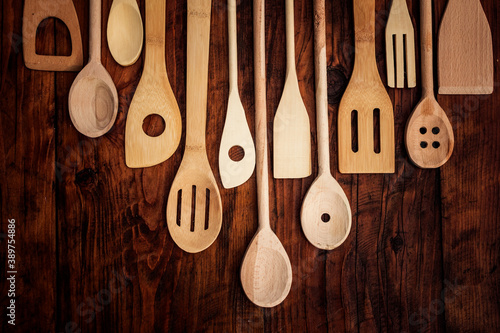 Wooden kitchen utensils on the rustic wood background with empty space for message. High angle view.