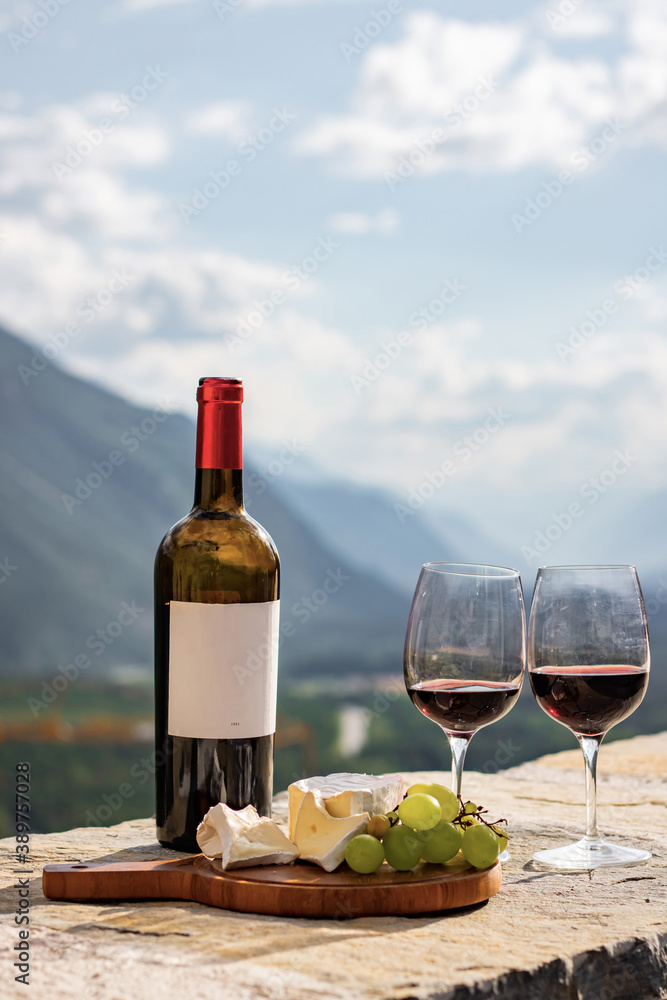 Obraz premium Glass of red wine and mountains on background. Swiss cheese and wine