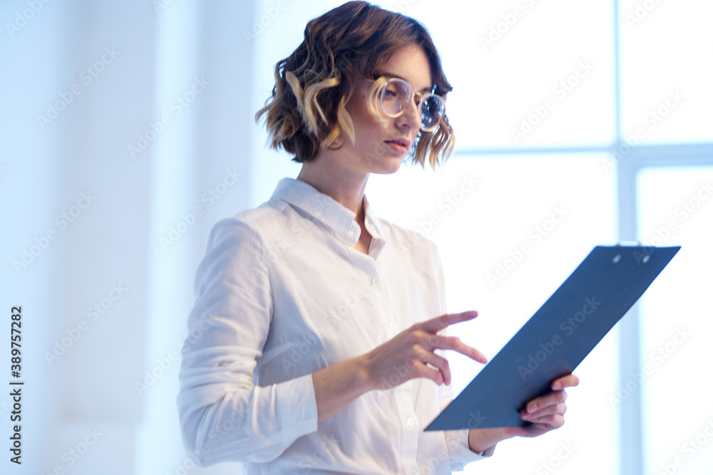 Business woman in the office with documents in the hands of the window in the background finance work Business woman in the office with documents in the hands of the window in the background finance work