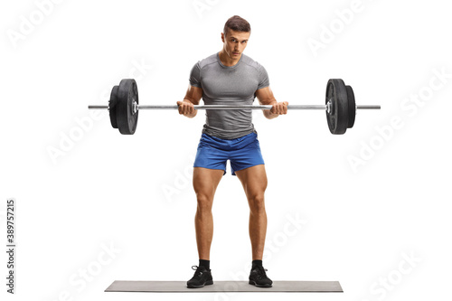 Full length portrait of a strong young man in sportswear lifting heavy weight