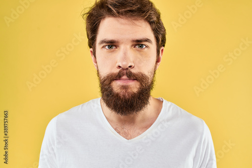 A man in a white t-shirt gestures with his hands lifestyle cropped view yellow background more fun © SHOTPRIME STUDIO