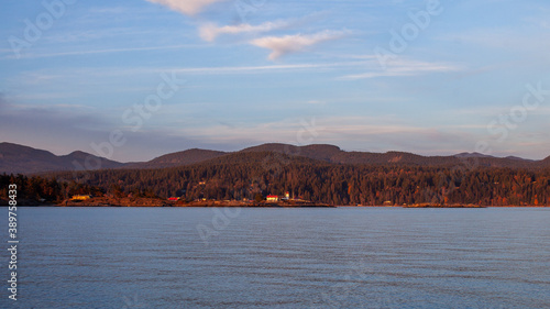 Fototapeta Naklejka Na Ścianę i Meble -  A view of Merry Island Lighthouse, along the Sunshine Coast at sunset, on the Pacific Ocean in British-Columbia. The lighthouse marks the entrance of Welcome Pass