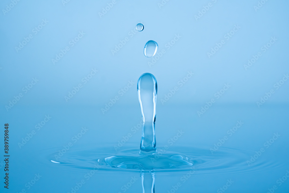 Water drop splashing into blue water surface Water drop splashing into blue water surface