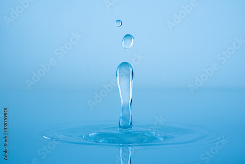 Water drop splashing into blue water surface