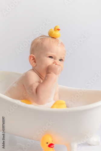 
we have fun playing and bathing with a baby in a white bath on a white background with ducks on the child's head