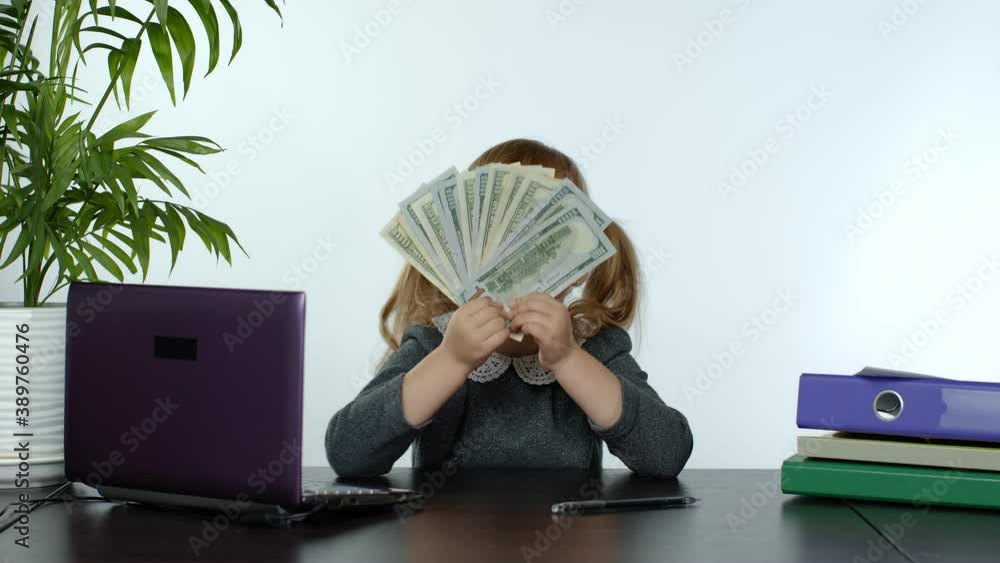 Child girl boss earns money. Little pretty boss kid hold much dollars cash in her hands on the table in the office. Finance and success business concept. White background. 6k downscale, slow motion Child girl boss earns money. Little pretty boss kid hold much dollars cash in her hands on the table in the office. Finance and success business concept. White background. 6k downscale, slow motion