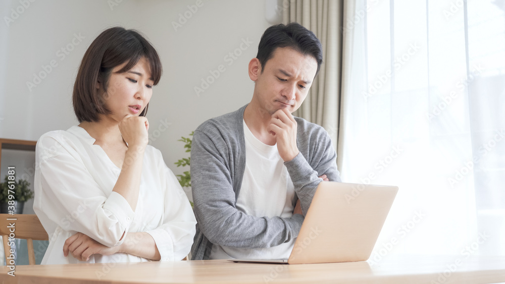 リビングでパソコンを見る夫婦・カップル リビングでパソコンを見る夫婦・カップル