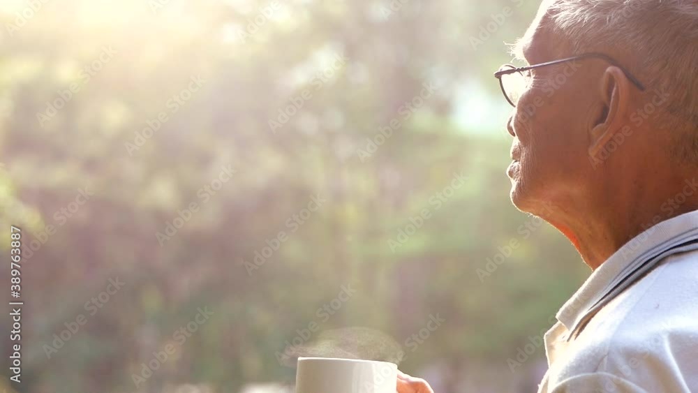 Side view of Asian senior drinking hot coffee outdoor and enjoying landscape on the mountain with sunlight in morning. Side view of Asian senior drinking hot coffee outdoor and enjoying landscape on the mountain with sunlight in morning.