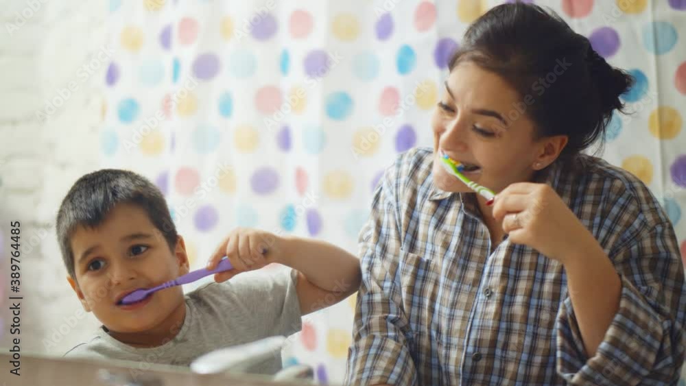 Mother and cute little son brushing teeth together in front of mirror in bathroom Mother and cute little son brushing teeth together in front of mirror in bathroom