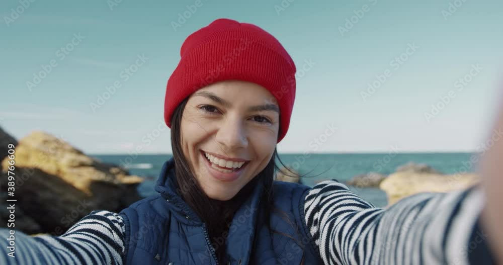 Close up of young beautiful woman posing holding camera in hands on sea background. Happy girl makes grimaces by shooting herself on video. Close up of young beautiful woman posing holding camera in hands on sea background. Happy girl makes grimaces by shooting herself on video.