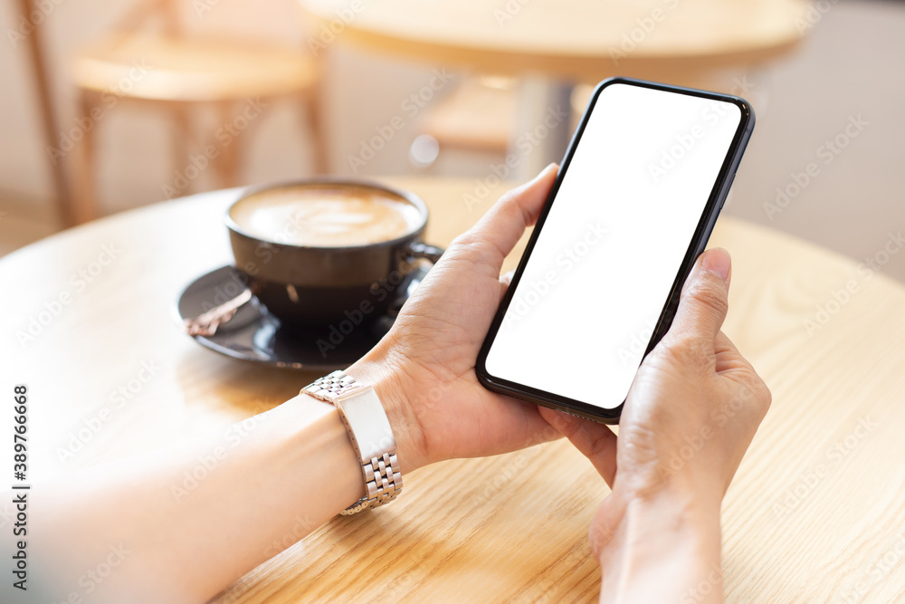 cell phone blank white screen mockup.woman hand holding texting using mobile on desk at coffee shop.background empty space for advertise.work people contact marketing business,technology