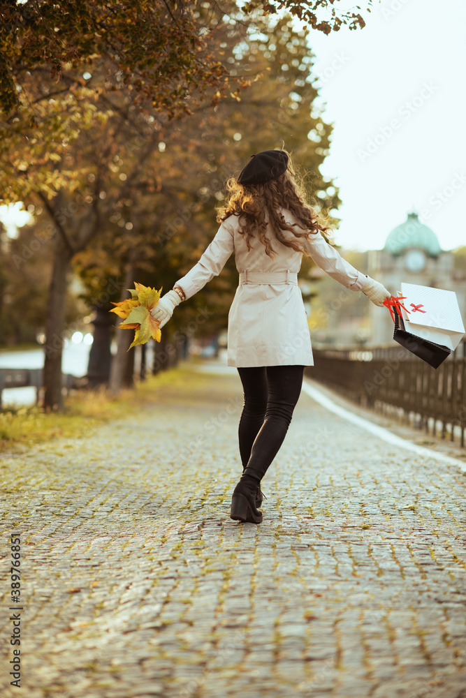 happy trendy woman with shopping bags and autumn leaves