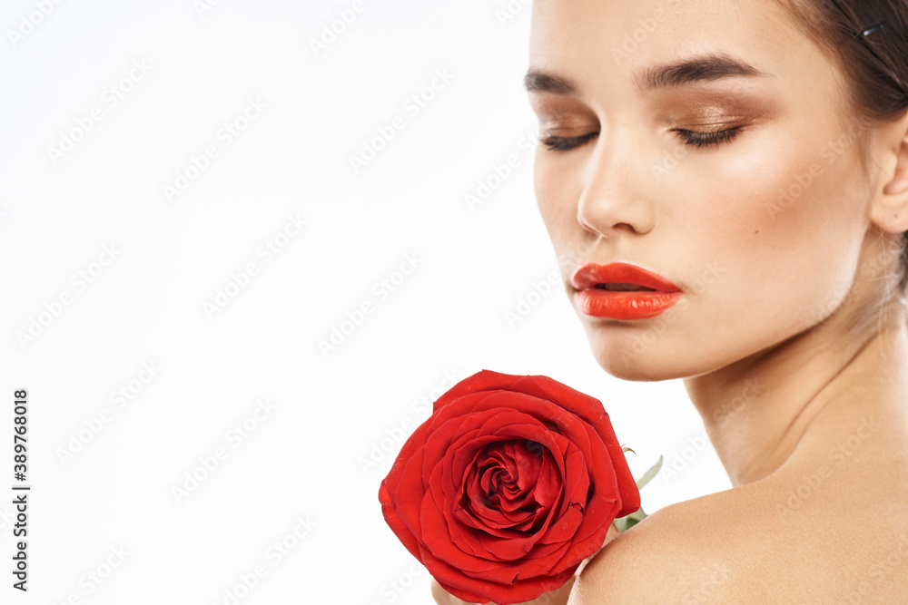 Beautiful woman with red rose near face makeup naked shoulders portrait