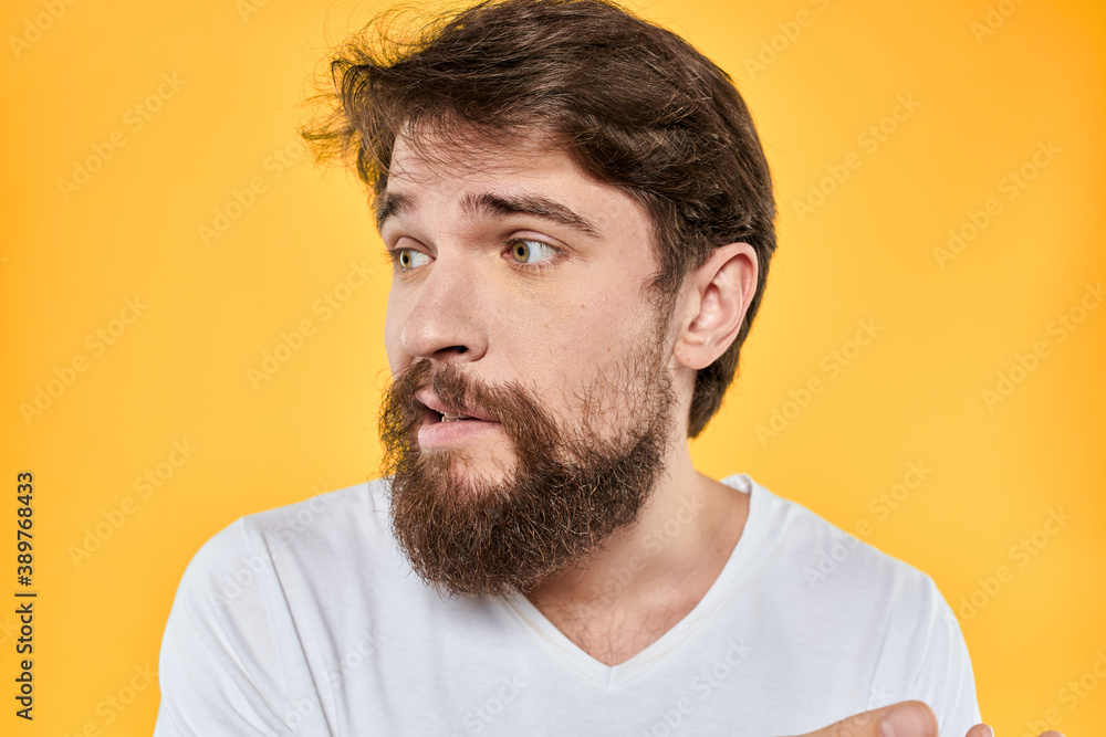 Man with emotional expression white t-shirt close-up studio yellow background Man with emotional expression white t-shirt close-up studio yellow background