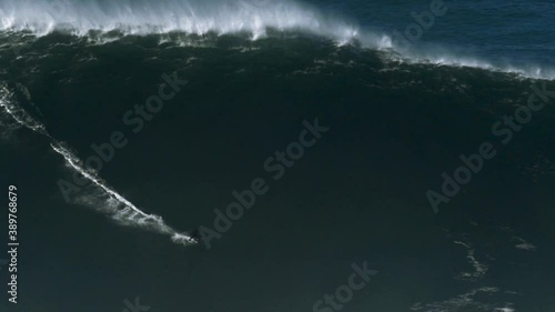 Slow motion of a big wave surfer riding a monster wave in Nazaré, Portugal. Nazaré is a small village in Portugal with the biggest waves in the world. Pure action! photo