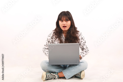 Portrait of an excited young beautiful girl holding laptop computer and celebrating success isolated over white background.
