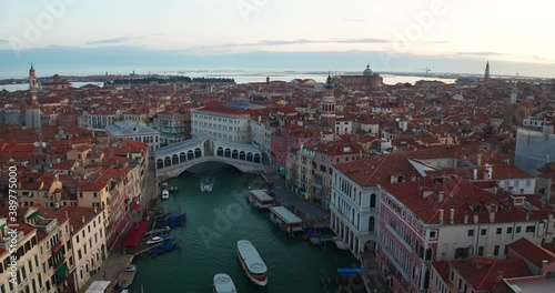 Aerial view of scenic panorama of famous landmark Rialto bridge of Canal Grande with gondolas and Basilica di Santa Maria della Salute with nobody during covid-19 lockdown at sunset in Venice, Italy.