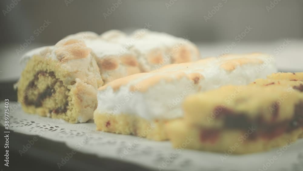 Close up of biscuit backery and a swiss roll with flambeed egg white cream and powdered sugar on top laying on a plate. Racking focus. Shot in 4K. Close up of biscuit backery and a swiss roll with flambeed egg white cream and powdered sugar on top laying on a plate. Racking focus. Shot in 4K.