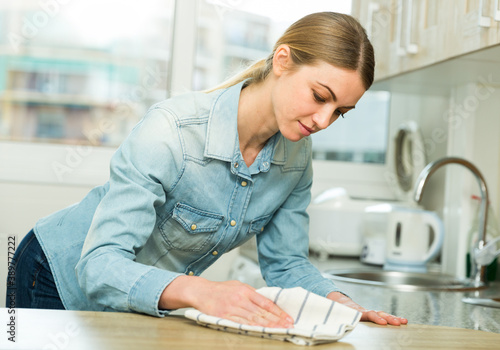 Positive housewife cleans the table in the kitchen. High quality photo photo