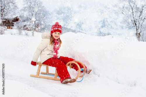 Girl on sleigh ride. Kids sled. Child with sledge