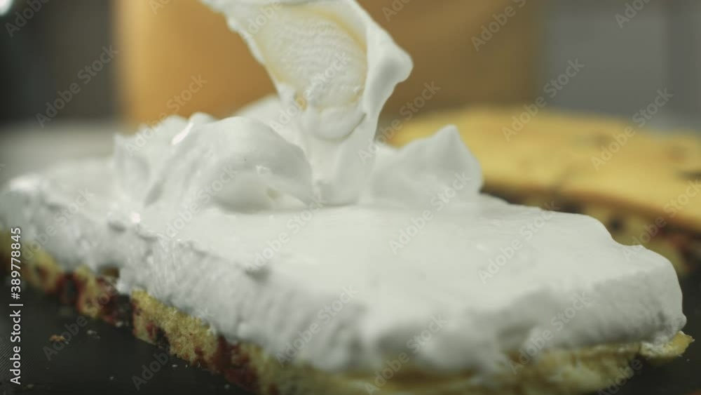 Close up of whipped egg white cream being put on a delicious swiss roll dough by a vegan chef with another cake in the background. Shot in 4K. Close up of whipped egg white cream being put on a delicious swiss roll dough by a vegan chef with another cake in the background. Shot in 4K.