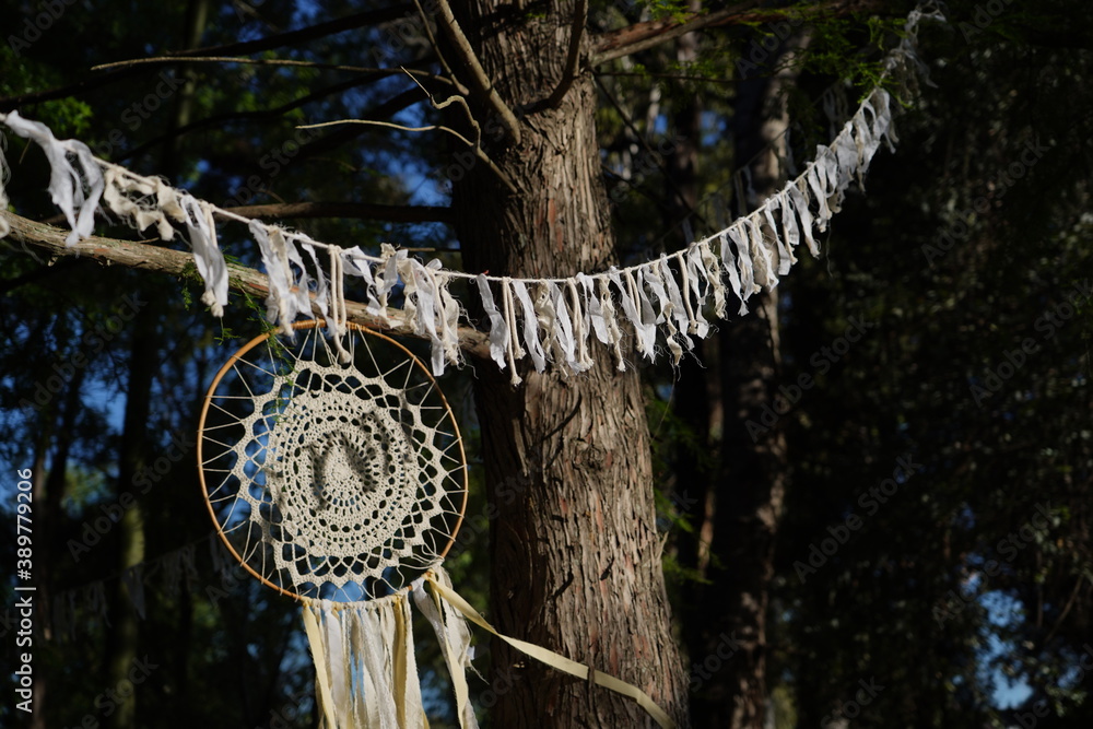 Dreamcatcher made of yarn. Handmade object placed between the trees of a field.