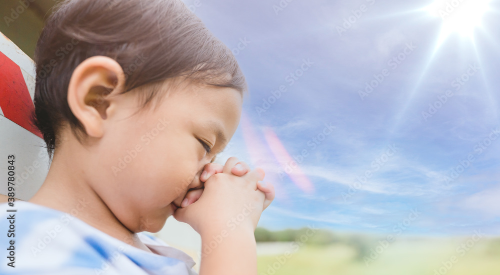 Little kid boy with praying hands worship and pray in morning.Prayer kid boy praise worship to GOD on blue sky nature background.Gratitude, Little kid boy with praying hands worship and pray in morning.Prayer kid boy praise worship to GOD on blue sky nature background.Gratitude,