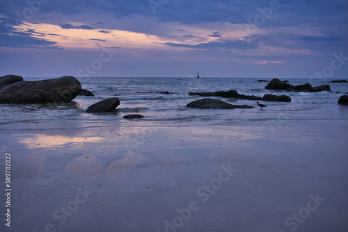 This unique photo shows the sunrise on Hua Hin Beach. You can see the first rays of the sun through the clouds and the big rocks on the beach