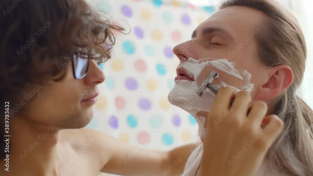 Close up of young gay couple shaving together in bathroom Close up of young gay couple shaving together in bathroom