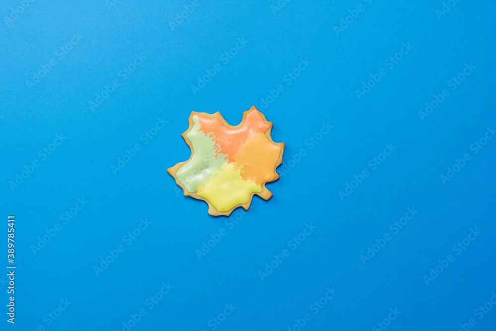 Sweet homemade leaf cookie with icing isolated on dark blue background minimal flat lay composition. Sweet homemade leaf cookie with icing isolated on dark blue background minimal flat lay composition.