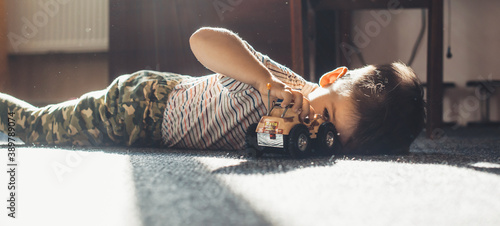 Lovely small boy playing on the floor with a toy car in a sunny day photo