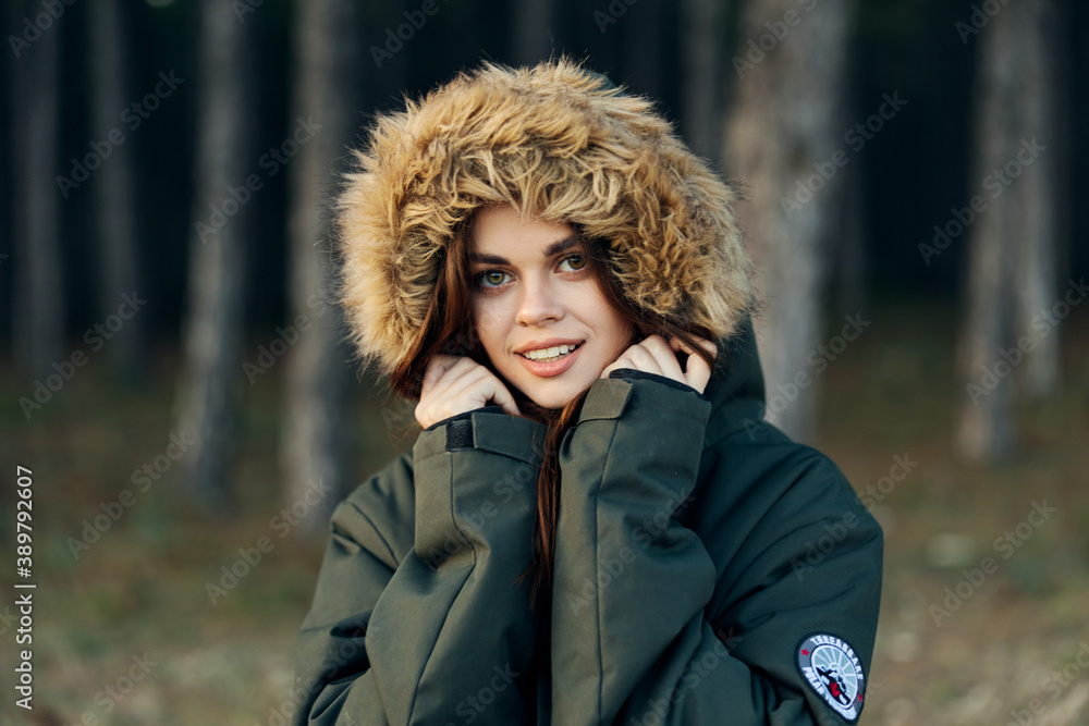 Woman in a jacket with a hood on her head close-up coolness on the background of the forest Woman in a jacket with a hood on her head close-up coolness on the background of the forest