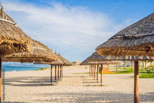 Beach with thatched umbrellas and wooden loungers