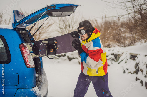 The snowboard does not fit into the car. A snowboarder is trying to stick a snowboard into a car. Humor, fun