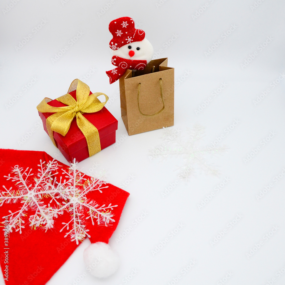 Christmas shopping bag and snowman, red gift box with gold ribbon, Santa hat and snowflakes on white background. Happy new year 2021. Copy space. Christmas shopping bag and snowman, red gift box with gold ribbon, Santa hat and snowflakes on white background. Happy new year 2021. Copy space.
