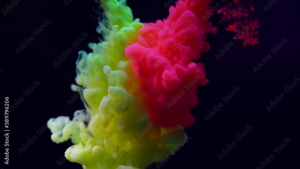 Abstract neon pink and yellow color paint mixing in water on black background Abstract neon pink and yellow color paint mixing in water on black background