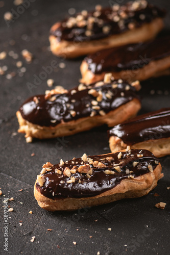 Chocolate eclairs filled with cream on dark background