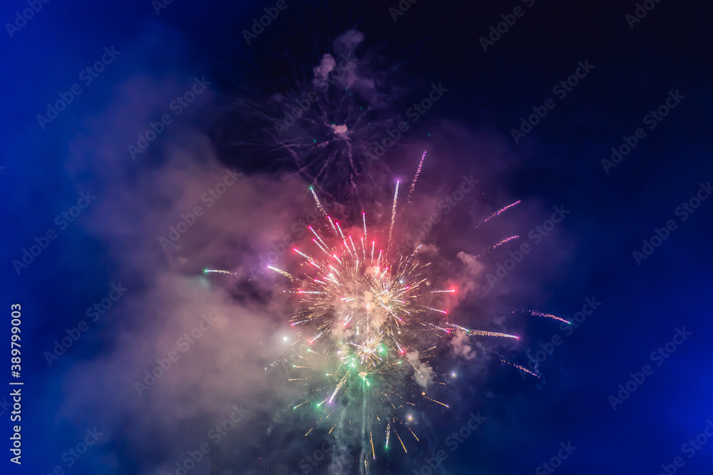 Beautiful colorful holiday fireworks in the evening sky with majestic clouds