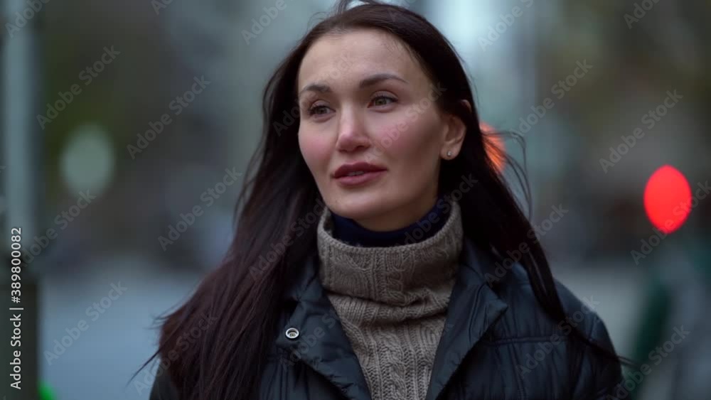 Portrait of an attractive middle-aged woman walking in the city square. Look thoughtful and a little sad
