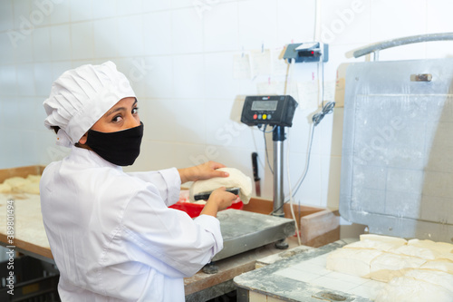 Bakery worker cuts raw dough with a knife © JackF